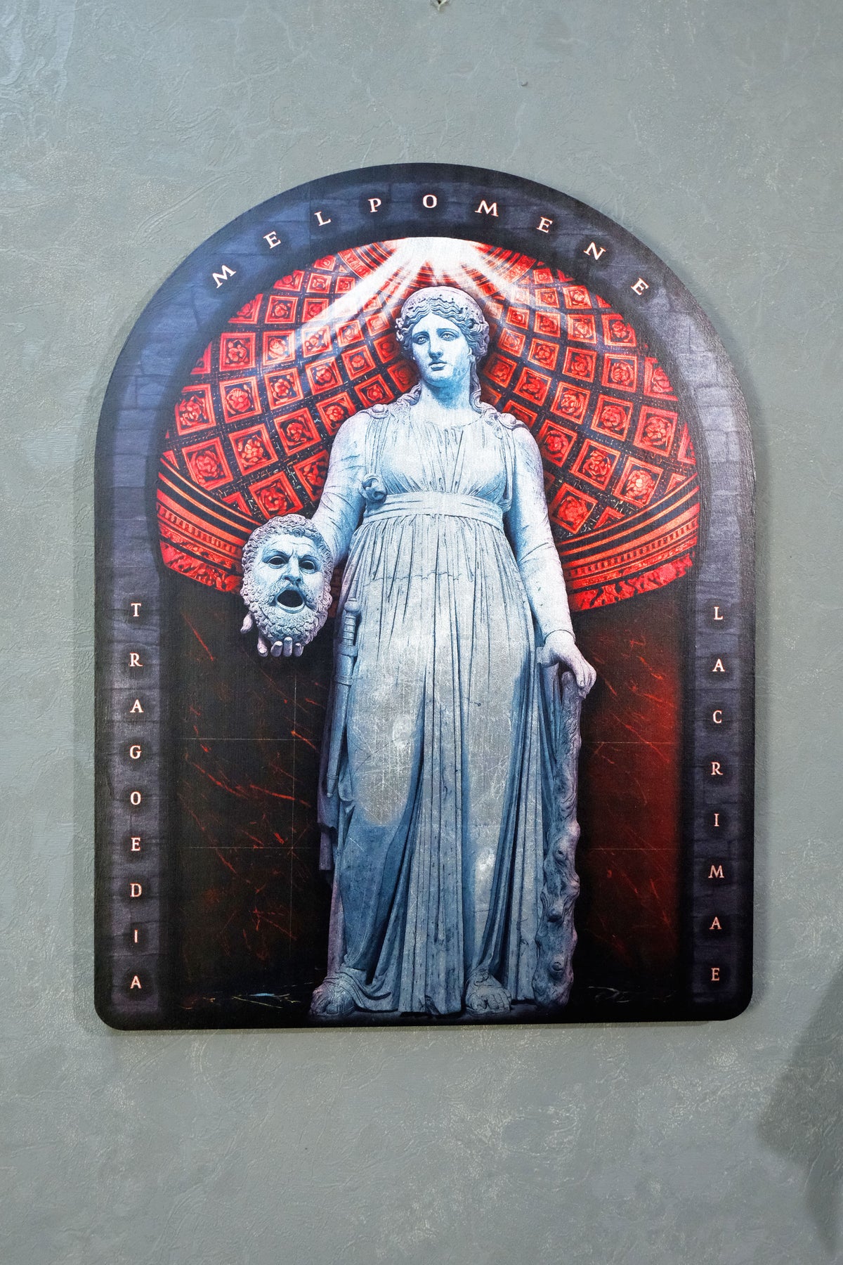 A framed wall art print featuring a pale blue statue of a woman holding a severed head, set against a red patterned arch and dark background, mounted on a gray wall. dark academia decor Melpomene
Muse of Tragedy