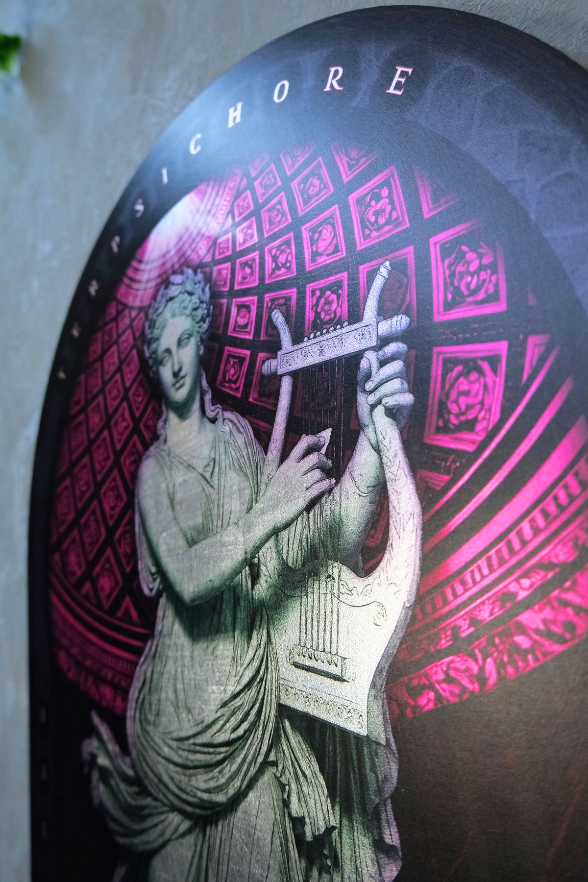 A close-up of a circular decorative plaque or wall art featuring a classical statue-like figure playing a lyre, with pink and magenta geometric patterns in the background and the word 'CHORUS' at the top. dark academia decor  Terpsichore — Muse of Dance
