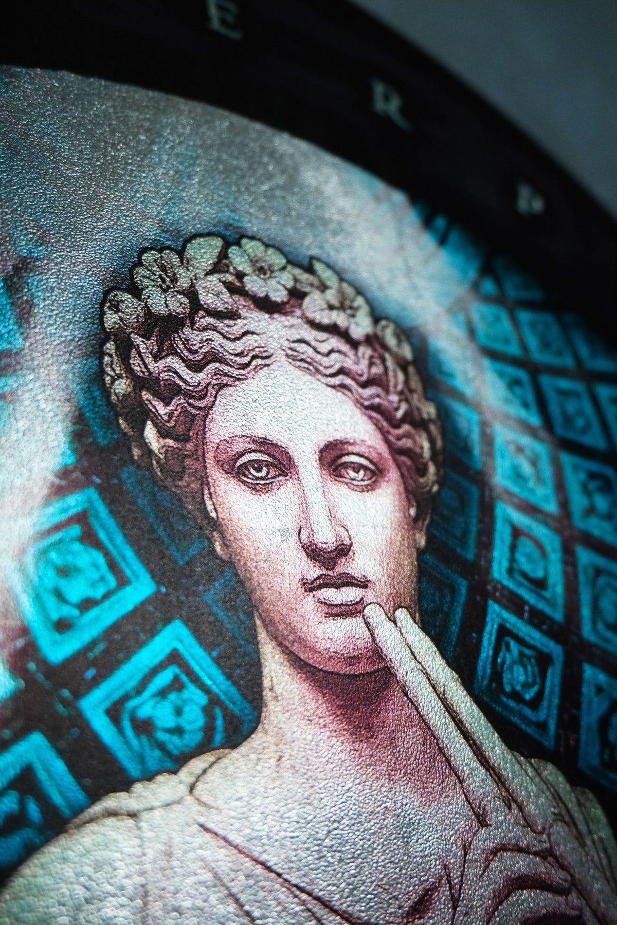 Close-up of a circular decorative wall art piece featuring a classical bust portrait in gray and black tones, with bright cyan-blue geometric patterns in the background. Euterpe — Muse of Music