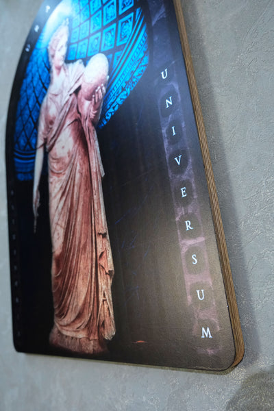 A close-up of a printed board or plaque showing a classical statue in warm beige tones against a dark background with blue architectural details, plus vertical text reading 'UNIVERSUM'. Urania is the Greek Muse of astronomy and astrology