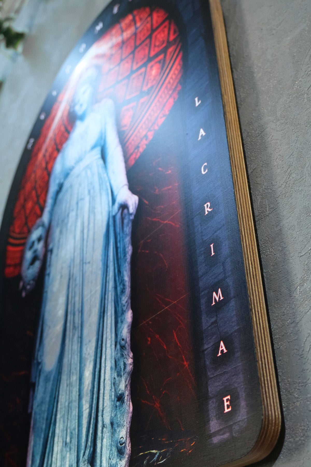 A close-up of a dark, gothic wall art print or poster featuring a ghostly woman in a long blue-gray dress against a red stained-glass-style background, with the word 'LACRIMA' printed vertically in white on the right side.dark academia decor  Melpomene
Muse of Tragedy