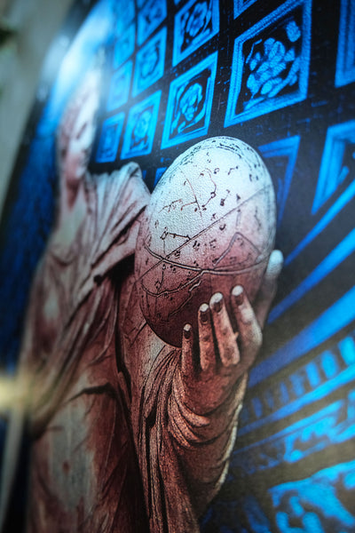 A close-up of a large printed artwork or poster showing a robed figure holding a detailed celestial globe, with blue geometric panel designs in the background. Urania is the Greek Muse of astronomy and astrology