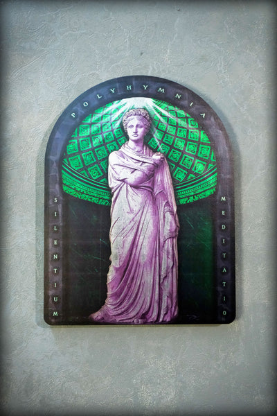A rectangular arched plaque featuring a purple statue of a draped woman against a green patterned background, mounted on a textured gray wall. Polyminia is a common alternative spelling of Polyhymnia (or Polymnia), the Greek Muse of sacred poetry, hymns