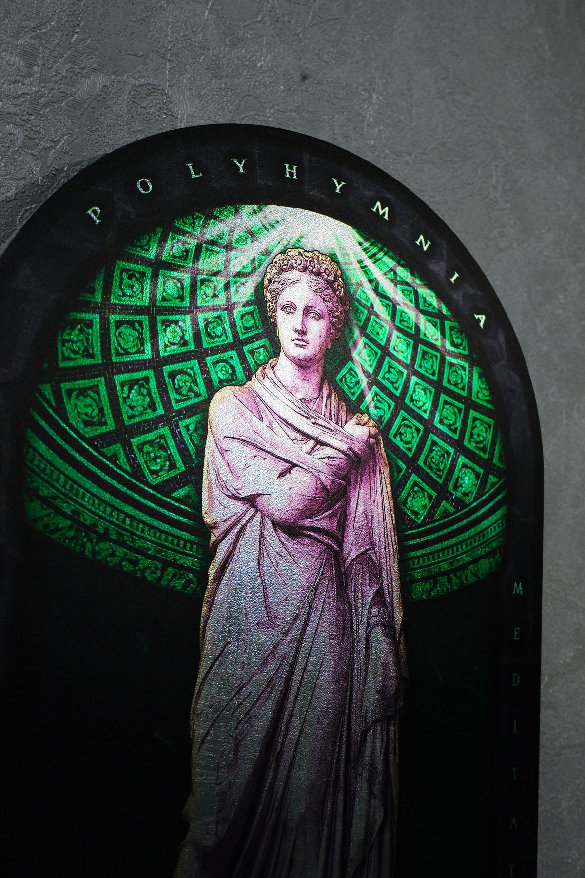 A stained glass window depicting a classical female figure in a draped gown, set against a green geometric pattern and framed by a black arch with the word 'POLYHYMNIA' at the top. Polyminia is a common alternative spelling of Polyhymnia (or Polymnia), the Greek Muse of sacred poetry, hymns