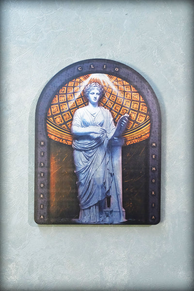 An arched decorative plaque featuring a classical statue of a draped female figure in blue-gray tones, set against a patterned gold and dark background, mounted on a textured light gray wall. dark academia decor  Clio — Muse of History